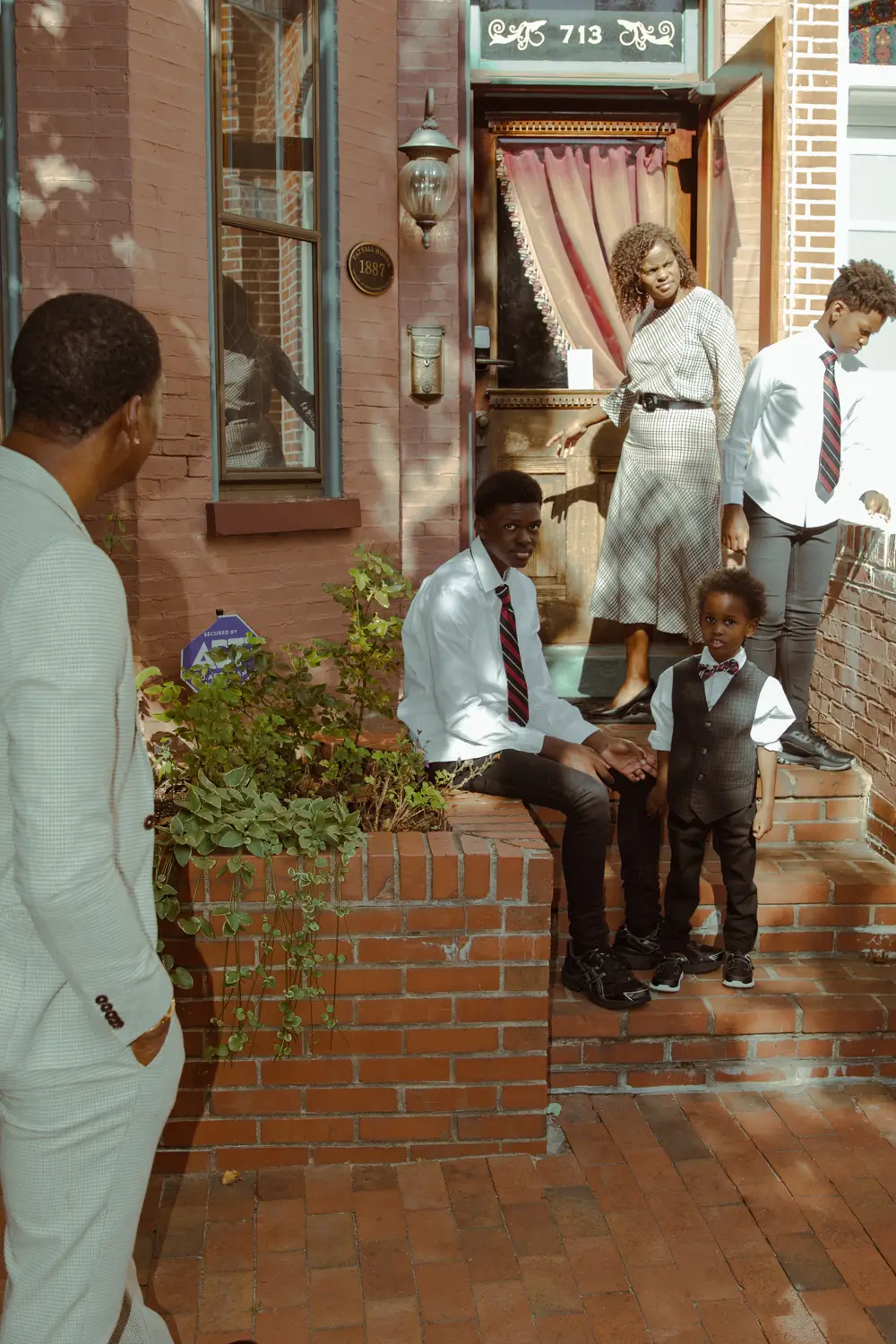 Casual portrait of a multi-generational Black family on a brick stoop outside their home in New York City